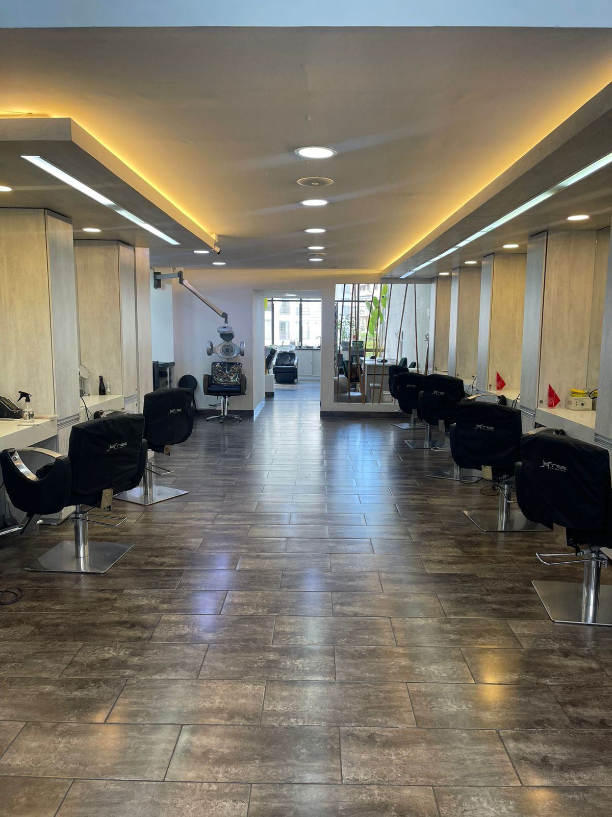 Salón de Jefree Peluquería: pasillo luminoso con tocadores y piso de madera